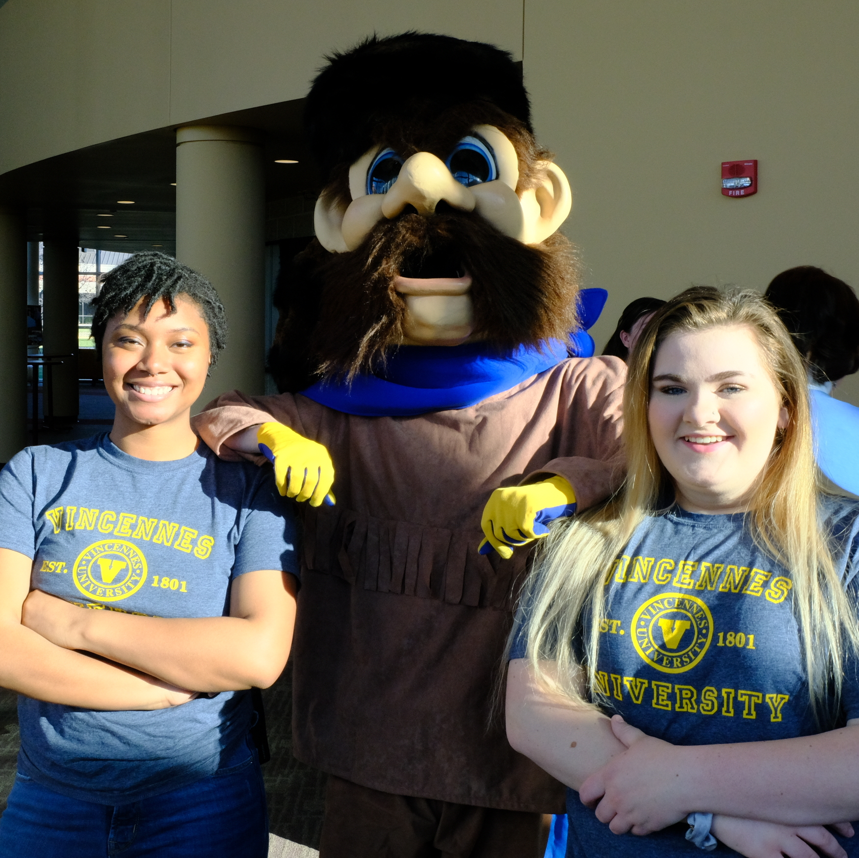 Two Vincennes University female students standing between VU mascot, Trailblazer Willie